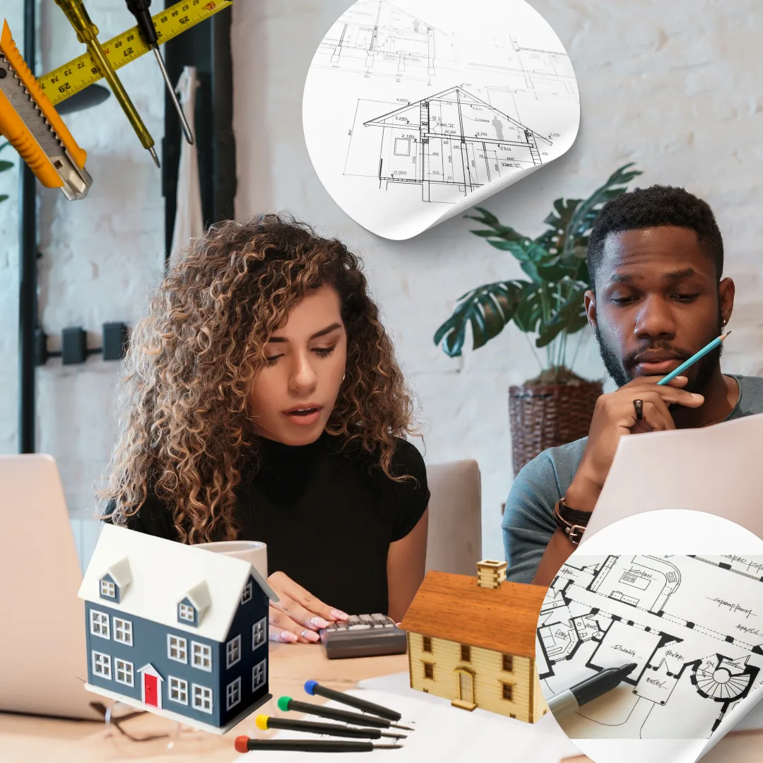 A couple reviewing house plans and calculations at a table with blueprints, model houses, and construction tools surrounding them.