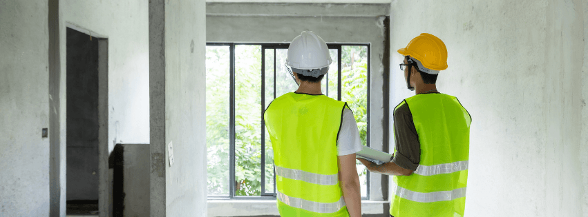 Our residential construction services with construction professionals in safety gear inspecting a residential project site with large windows and natural light.