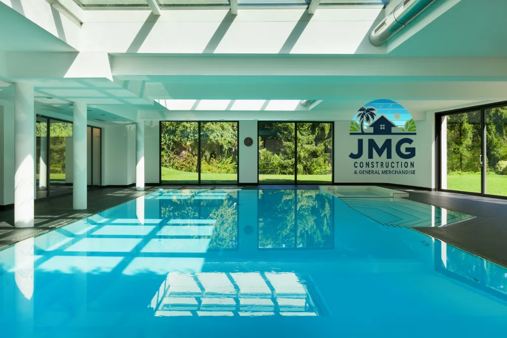 Swimming pool services in cagayan de oro city – jmg construction Indoor swimming pool with modern design, featuring natural lighting and lush greenery outside, representing swimming pool services by jmg construction in cagayan de oro city, northern mindanao, philippines.