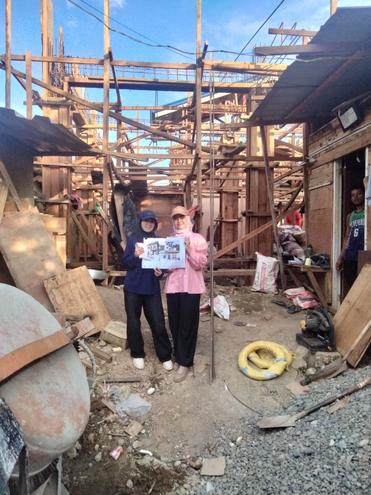 Three jmg design & build interns standing in front of timber scaffolding at the kisanlu construction site