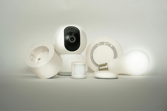 🔐 security & smart systems A set of smart home devices including a camera, smoke detector, motion sensor, and smart plug arranged neatly on a white surface.