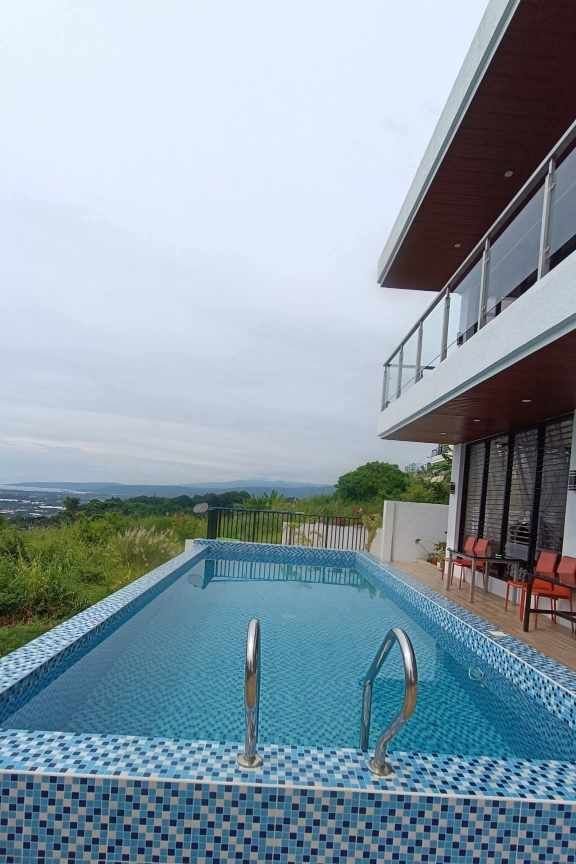 Teakwood hills luxury mansion – cagayan de oro 8 Poolside deck with glass door access and seating area