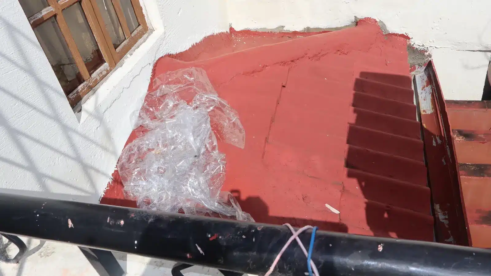 Property condition assessment & indicative value range: camella gran europa, lumbia, cagayan de oro 15 Red-painted exterior stair landing with patched cement edges at the wall and a crumpled plastic sheet, camella gran europa house, cagayan de oro