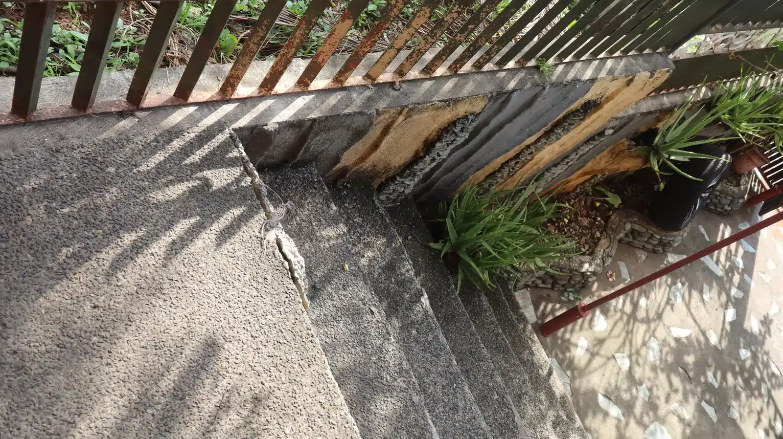 Property condition assessment & indicative value range: camella gran europa, lumbia, cagayan de oro 12 Cracked concrete entry steps beside a rusted railing base and a planter with deteriorated wood, camella gran europa house, cagayan de oro