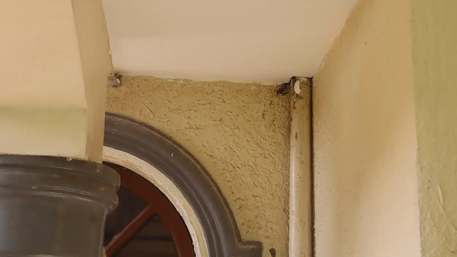 Property condition assessment & indicative value range: camella gran europa, lumbia, cagayan de oro 19 Porch ceiling corner and textured wall above an arched opening with a vertical pipe at the corner, camella gran europa house, cagayan de oro
